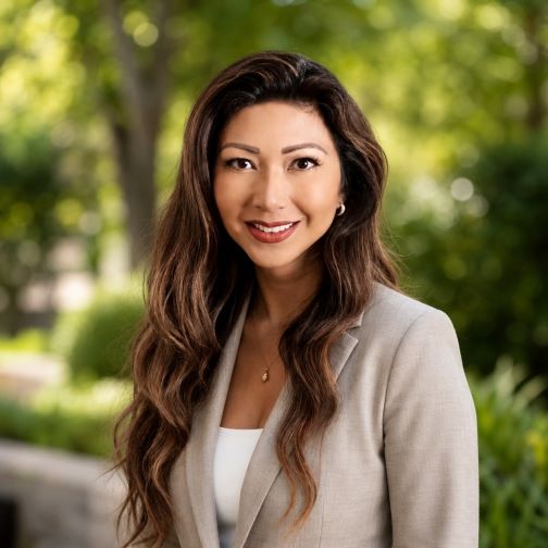 Beverly Salcedo headshot, standing in front of a grassy leafy background